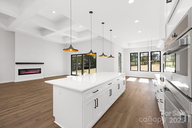 kitchen with dark hardwood / wood-style flooring, stainless steel oven, a center island, white cabinetry, and hanging light fixtures