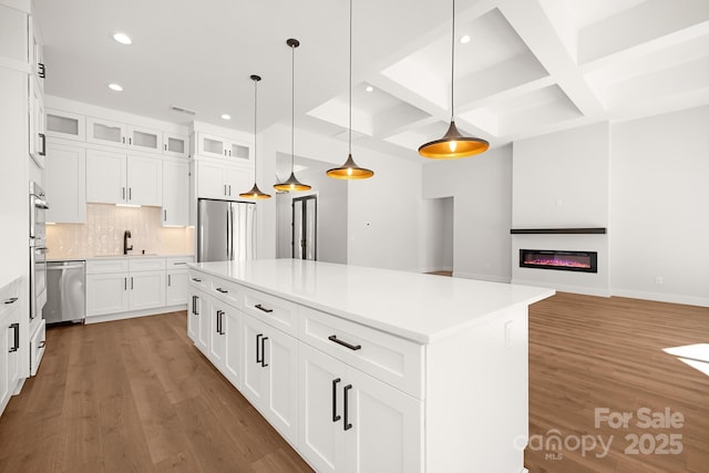 kitchen featuring decorative light fixtures, white cabinetry, appliances with stainless steel finishes, and coffered ceiling