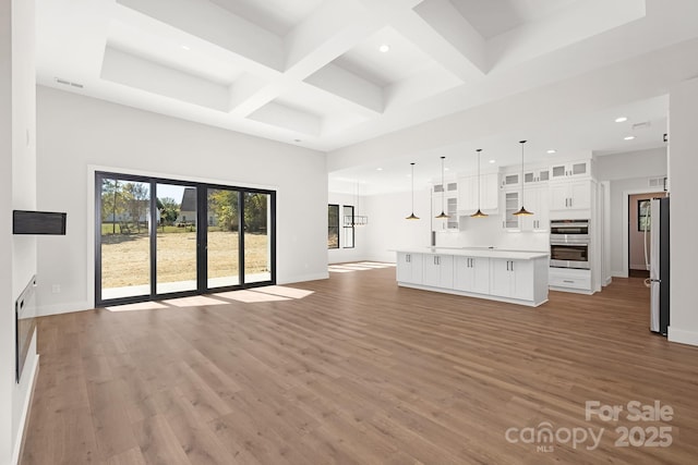 unfurnished living room with beam ceiling, wood-type flooring, and coffered ceiling