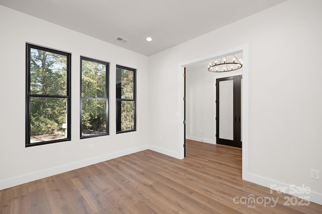 unfurnished room with wood-type flooring and an inviting chandelier