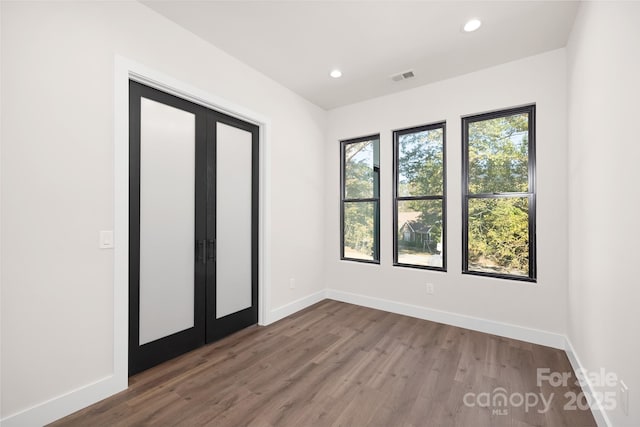 unfurnished bedroom with dark hardwood / wood-style flooring, french doors, and multiple windows