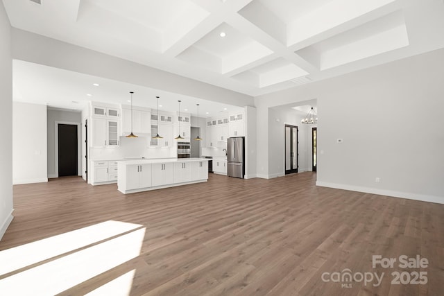 unfurnished living room with beamed ceiling, wood-type flooring, an inviting chandelier, and coffered ceiling