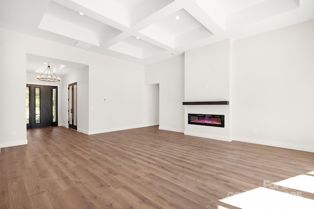 unfurnished living room featuring beamed ceiling, light wood-type flooring, coffered ceiling, and a notable chandelier