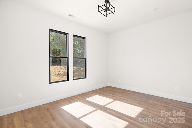 spare room featuring hardwood / wood-style floors and an inviting chandelier