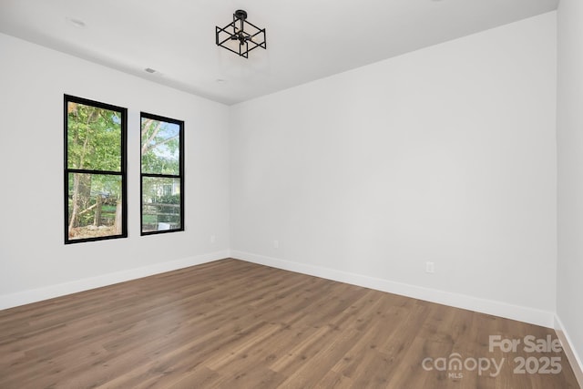 spare room featuring a chandelier and hardwood / wood-style flooring