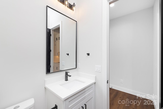 bathroom featuring wood-type flooring, vanity, and toilet