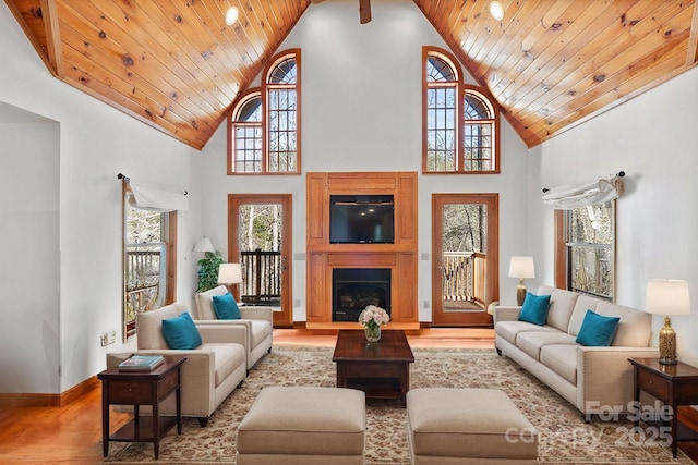 living room with wood ceiling, high vaulted ceiling, and a fireplace with raised hearth