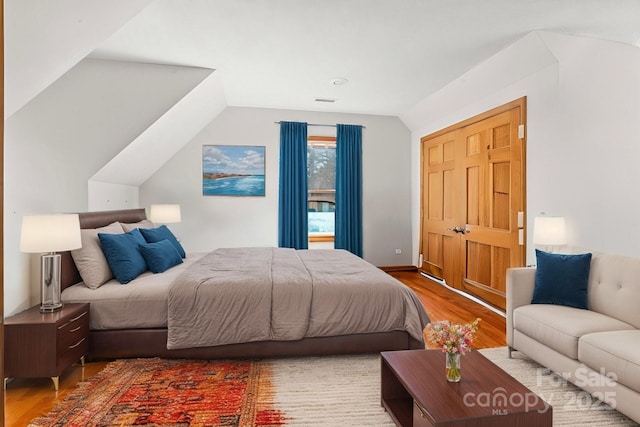 bedroom featuring visible vents, vaulted ceiling, and wood finished floors