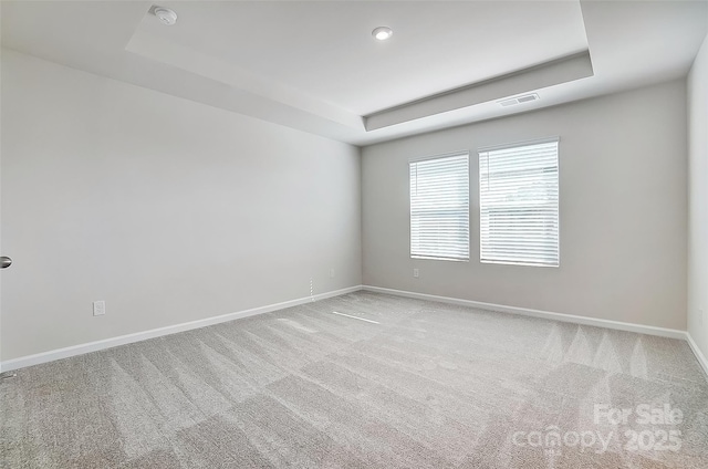 carpeted empty room featuring a tray ceiling