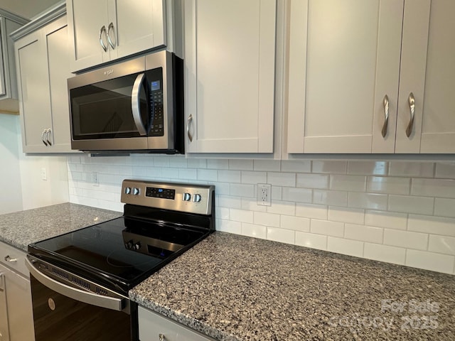 kitchen featuring decorative backsplash, dark stone counters, and appliances with stainless steel finishes