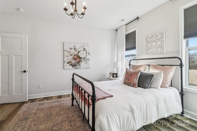 bedroom featuring multiple windows, dark hardwood / wood-style flooring, and a chandelier