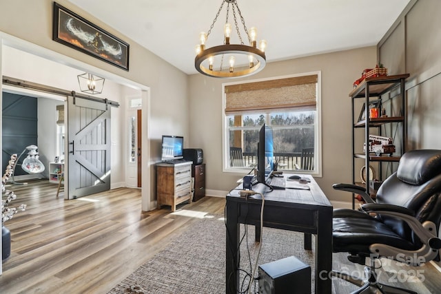 office area featuring a barn door, an inviting chandelier, and light hardwood / wood-style flooring