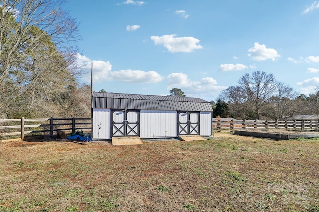 view of outbuilding featuring a rural view and a lawn