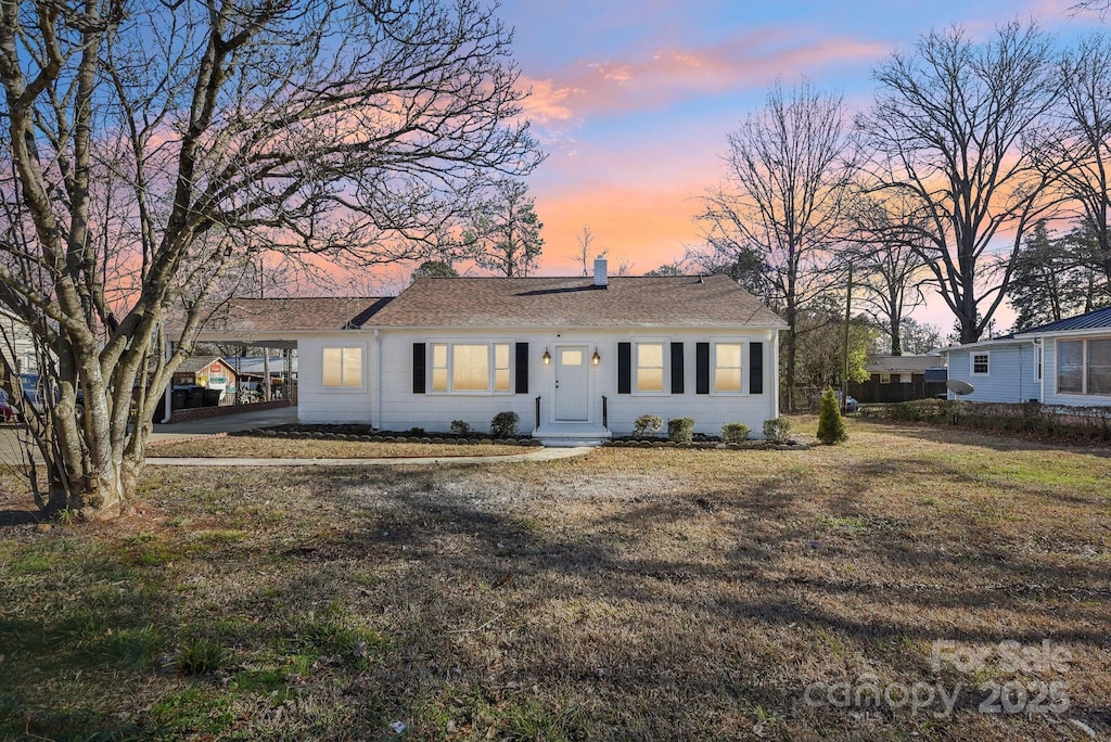 ranch-style home with a carport and a lawn