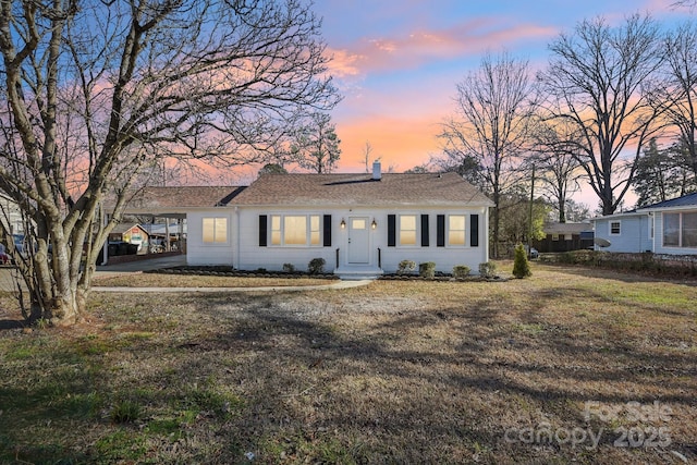 ranch-style home with a carport and a lawn