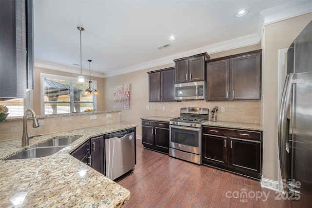 kitchen featuring sink, light stone counters, decorative light fixtures, dark brown cabinets, and appliances with stainless steel finishes