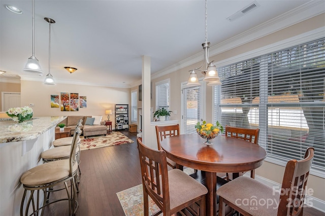 dining space with ornamental molding and dark hardwood / wood-style flooring