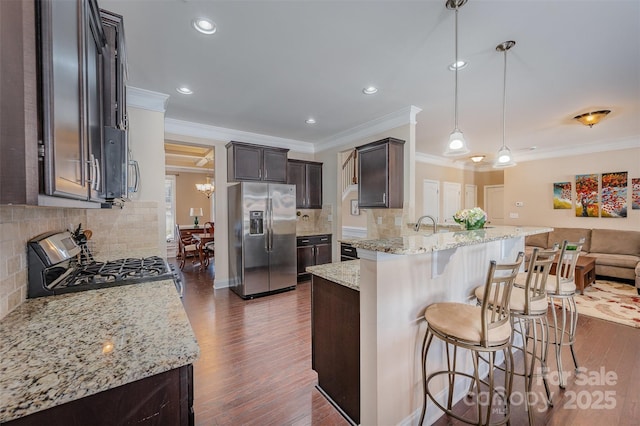 kitchen with light stone counters, appliances with stainless steel finishes, decorative light fixtures, and backsplash