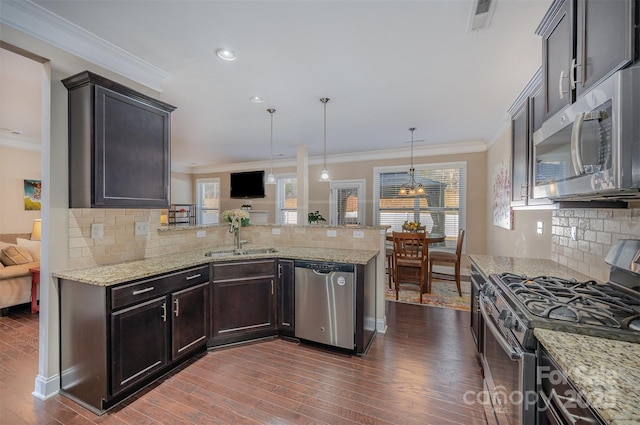 kitchen featuring sink, appliances with stainless steel finishes, tasteful backsplash, decorative light fixtures, and kitchen peninsula