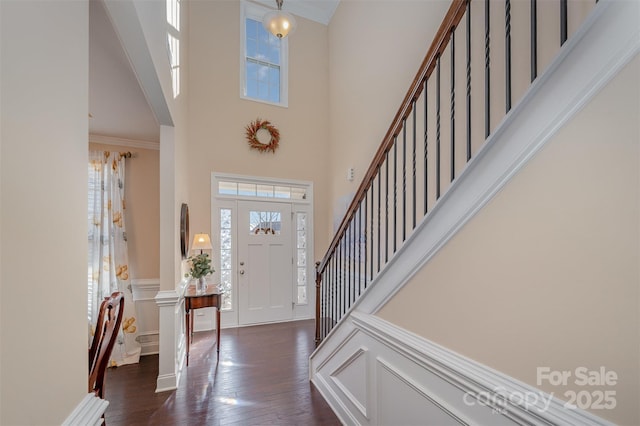 foyer featuring a towering ceiling, ornamental molding, and dark hardwood / wood-style floors