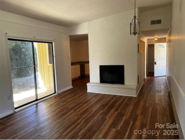 unfurnished living room with dark hardwood / wood-style flooring, lofted ceiling, and a brick fireplace