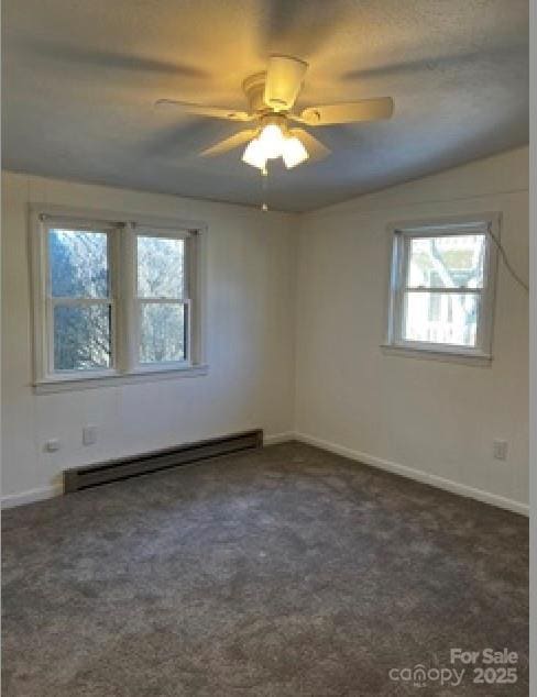 spare room with baseboard heating, ceiling fan, and dark colored carpet