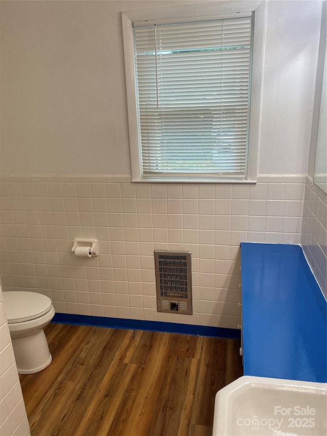 110 Heywood Rd Unit 20, Arden, NC 28704 - bathroom featuring tile walls, toilet, wood finished floors, a wainscoted wall, and heating unit