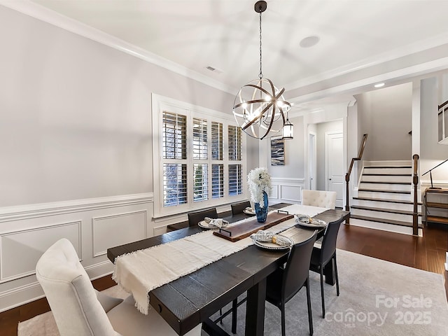 dining room featuring ornamental molding, dark wood-type flooring, and an inviting chandelier