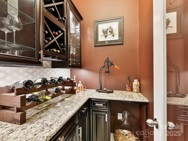 interior space featuring backsplash, light stone countertops, and dark brown cabinets