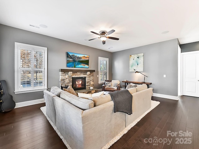 living room with a stone fireplace, ceiling fan, and dark hardwood / wood-style floors