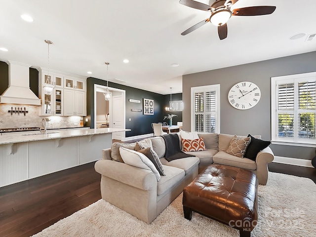 living room featuring sink, light hardwood / wood-style floors, and ceiling fan with notable chandelier