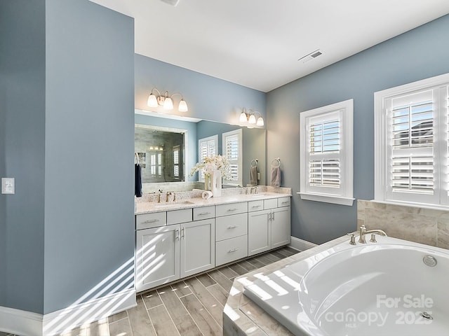 bathroom featuring tiled bath and vanity