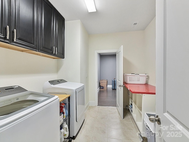 laundry area featuring washer and clothes dryer, light tile patterned floors, and cabinets