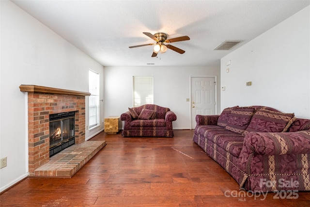 living room with ceiling fan, dark wood-type flooring, a textured ceiling, and a fireplace