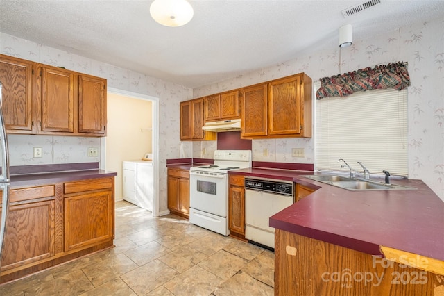 kitchen with a textured ceiling, separate washer and dryer, sink, and white appliances