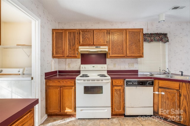 kitchen featuring white appliances, a textured ceiling, washing machine and dryer, sink, and light tile patterned floors