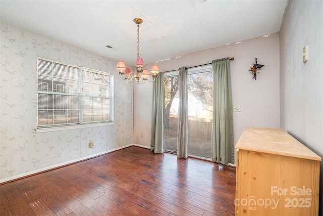 unfurnished dining area with dark hardwood / wood-style flooring and a chandelier