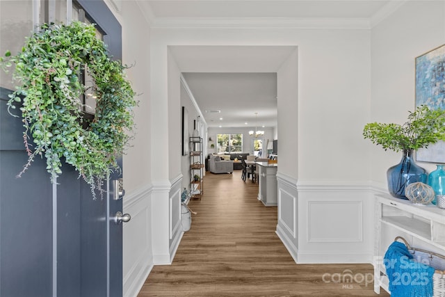 entrance foyer featuring crown molding, hardwood / wood-style floors, and a notable chandelier