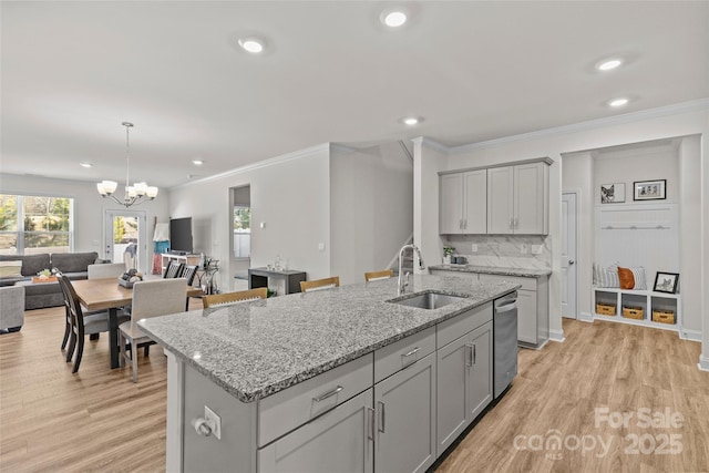 kitchen featuring decorative backsplash, light stone counters, a kitchen island with sink, sink, and gray cabinets