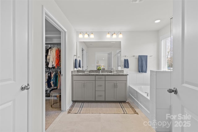 bathroom with tile patterned floors, a tub, and vanity