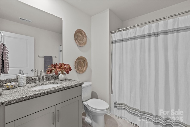 bathroom featuring tile patterned flooring, vanity, toilet, and walk in shower