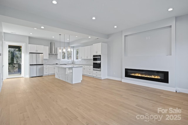 kitchen with white cabinetry, decorative backsplash, stainless steel appliances, and wall chimney range hood