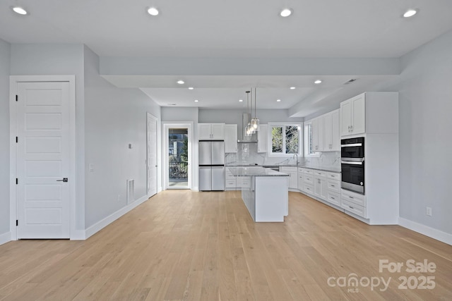 kitchen featuring white cabinetry, a center island, stainless steel appliances, backsplash, and decorative light fixtures