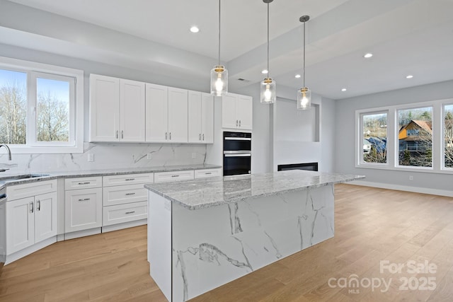 kitchen with white cabinetry, sink, and a kitchen island