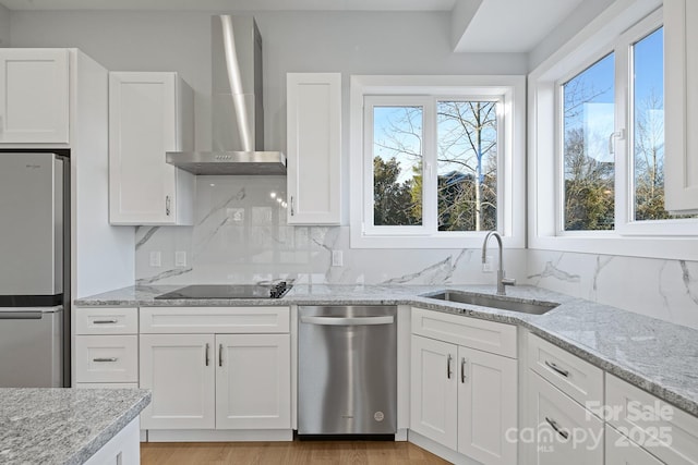 kitchen with sink, white cabinets, wall chimney range hood, and appliances with stainless steel finishes