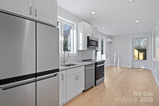 kitchen featuring white cabinetry, sink, tasteful backsplash, a wall mounted AC, and appliances with stainless steel finishes