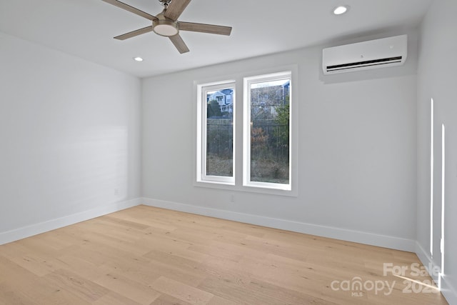 spare room with light wood-type flooring, a wall mounted AC, and ceiling fan