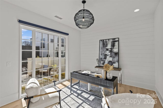 home office with wood walls and light hardwood / wood-style floors