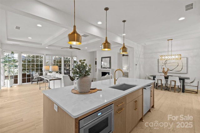 kitchen with sink, an island with sink, decorative light fixtures, and appliances with stainless steel finishes