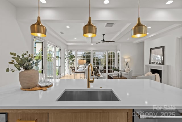 kitchen with beamed ceiling, dishwashing machine, pendant lighting, ceiling fan, and sink